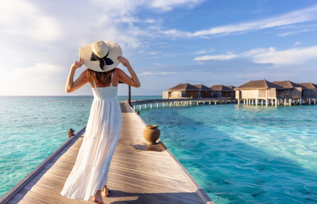 A traveler walking along a pier towards overwater bungalows in the Maldives, a luxurious South Asian Gem surrounded by crystal-clear waters.