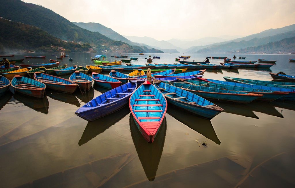 Colorful boats docked on Phewa Lake in Pokhara, Nepal, offering a serene glimpse of the natural beauty found in South Asian Gems.
