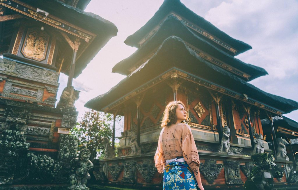 A traveler exploring the intricate architecture of a temple in Ubud, Bali, capturing the cultural beauty of South Asian Gems.