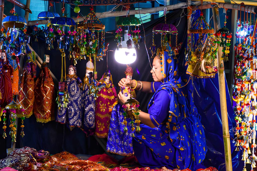 Woman arranging colorful traditional handicrafts and decorative puppets at a vibrant Dilli Haat market stall in Delhi.