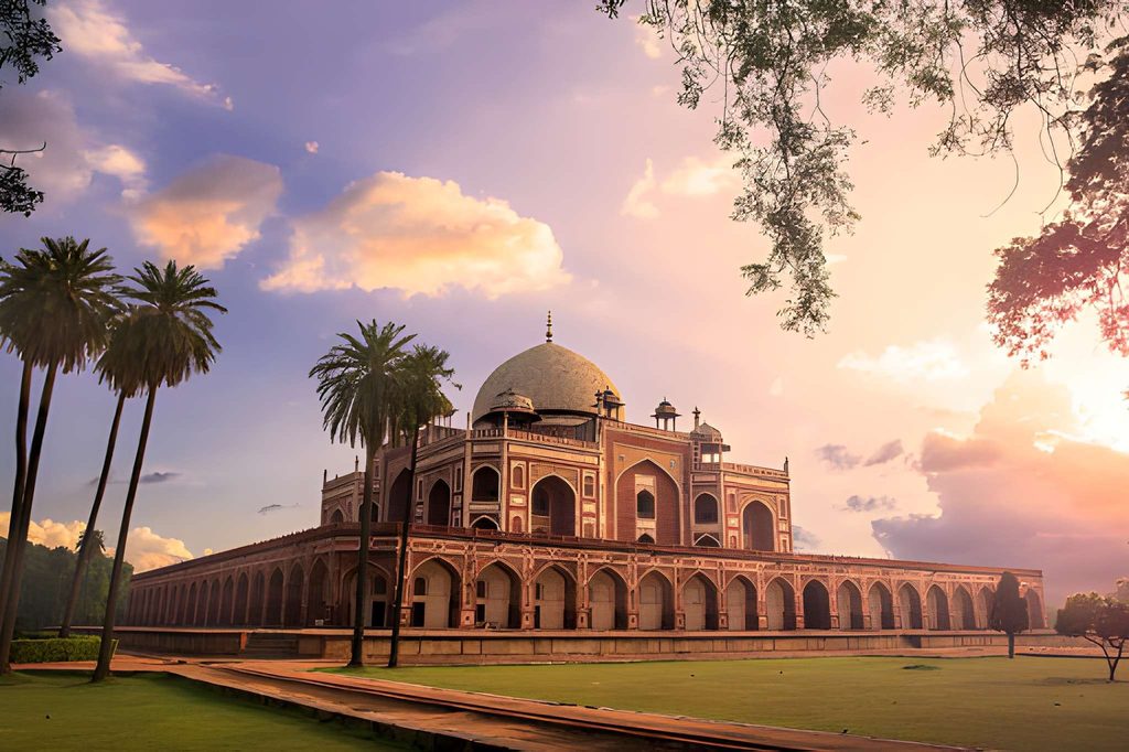 Humayun’s Tomb in Delhi surrounded by green lawns and tall palm trees, illuminated by warm sunset light beneath a colorful evening sky.